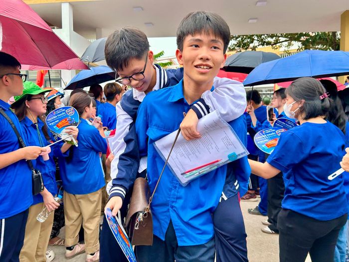 Một thí sinh bị thương ở chân được thanh niên tình nguyện cõng ra chỗ người nhà chờ đón. Ảnh: Trần Oanh.