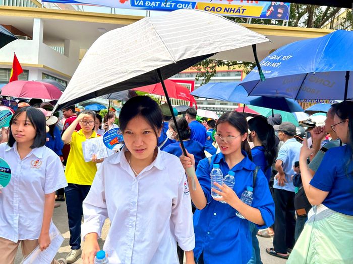 Tình nguyện viên phát nước, che ô cho các thí sinh sau khi hoàn thành môn thi ngữ văn. Ảnh: Trần Oanh.