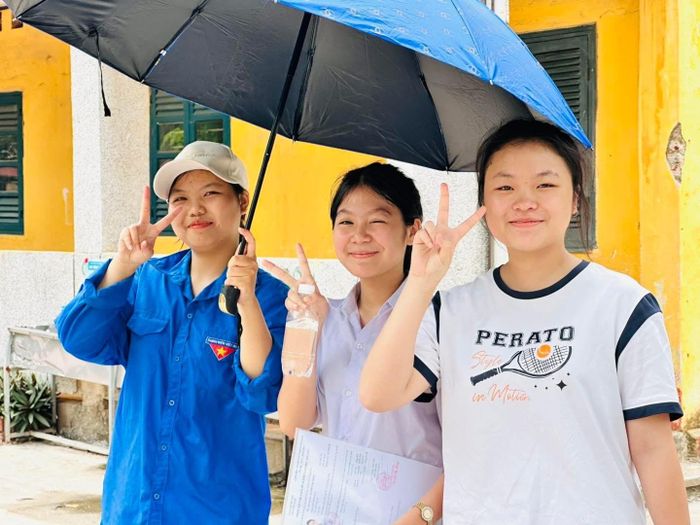 Hai thí sinh vui vẻ chụp ảnh cùng thanh niên tình nguyện. Ảnh: Tùng Nguyễn.