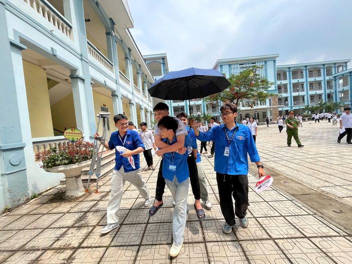 Một thí sinh bị đau chân, khó di chuyển đã được thanh niên tình nguyện hỗ trợ vào phòng thi. Ảnh: PV
