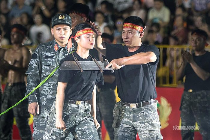Trước giờ biểu diễn tại Hội thao Công an nhân dân năm 2026, nữ chiến sĩ được đồng đội hỗ trợ kiểm tra tư thế và điểm tiếp xúc giữa yết hầu với lưỡi đao.
