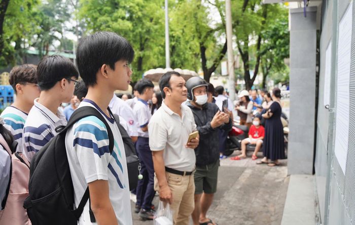  Thí sinh xem danh sách phòng thi tại điểm thi Trường THCS Nguyễn Du. Ảnh: THUẬN VĂN 
