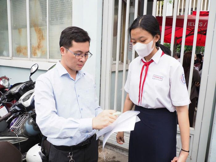  Thầy Vũ Văn Quyết, giáo viên chủ nhiệm lớp 9A1, Trường THCS Thanh Đa (phường Bình Quới) điểm danh học sinh của mình tại cổng điểm thi THCS Đống Đa. Ảnh: THU TÂM 