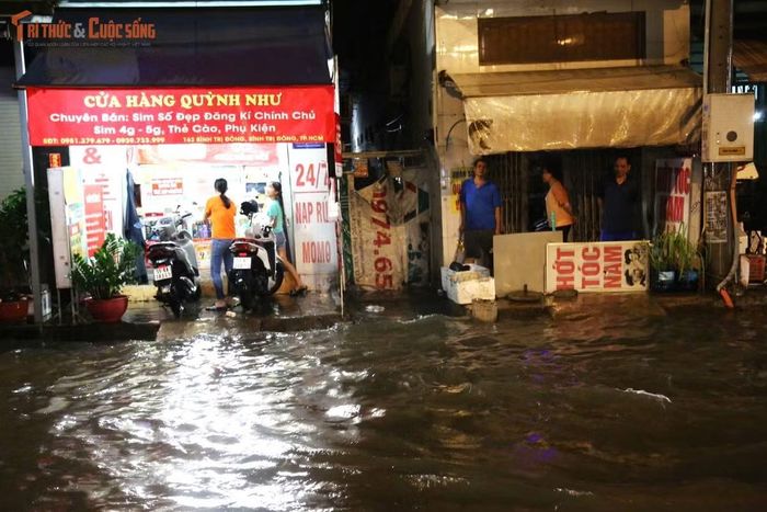Nước ngập tràn vào trước cửa nhiều cửa hàng, quán ăn dọc đường Bình Trị Đông khiến hoạt động kinh doanh bị đình trệ. Nhiều người dân phải kê cao hàng hóa để tránh bị hư hỏng.
