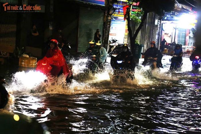 Dòng xe nối đuôi nhau di chuyển chậm chạp giữa biển nước trên đường Bình Trị Đông. Người lớn vất vả điều khiển xe, trẻ nhỏ mệt mỏi ngồi sau yên. Người đi bộ phải men sát nhà dân để tránh các hố ga bị nước che khuất.