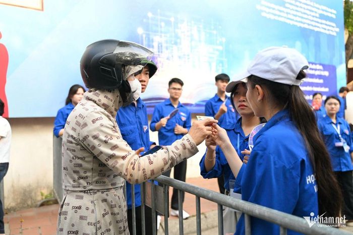 Tại điểm thi Trường THPT Xuân Đỉnh, một phụ huynh kịp thời mang căn cước công dân đến cho con và được lực lượng thanh niên tình nguyện hỗ trợ nhiệt tình. Ảnh: Nguyễn Huy