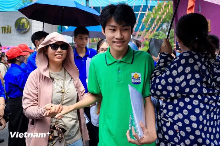 Những cái nắm tay thật chặt động viên con sau giờ thi. (Ảnh: Hoài Nam/Vietnam+)