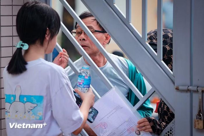 Thậm chí, đến giờ lên phòng thi sắp bắt đầu, vẫn có sự chăm sóc ân cần sau cánh cổng. (Ảnh: Hoài Nam/Vietnam+)