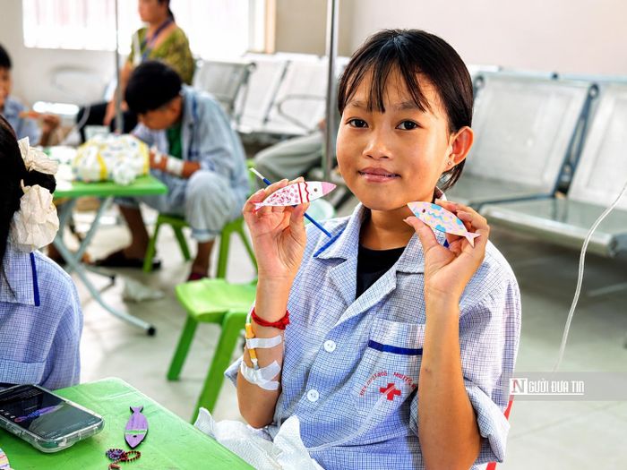 Thu Hằng cầm trên tay những chú cá gỗ do chính mình tô màu trong buổi sinh hoạt cùng các bệnh nhi.