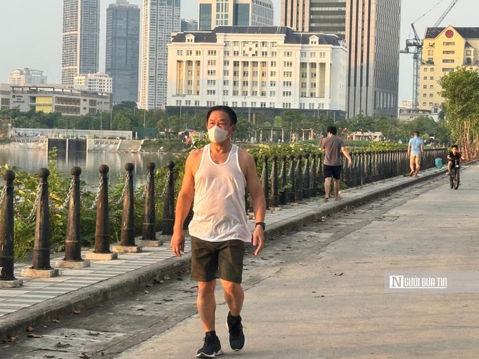 Người dân đi bộ phải bịt khẩu trang do mùi hôi thối bốc lên từ dưới mặt hồ.