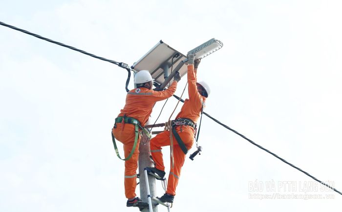 Nhân viên Điện lực Tràng Định lắp đặt đèn chiếu sáng sử dụng năng lượng mặt trời trên trục đường thôn Pò Lạn, xã Quốc Việt