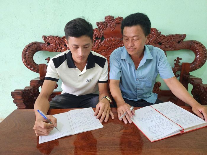Anh Hạng A Minh, Bí thư Chi bộ bản Tân Lập (bên phải) hướng dẫn quần chúng ưu tú Hạng A Sinh viết lý lịch xin vào đảng