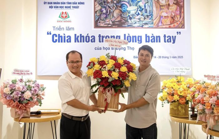 Nhà văn Đặng Bá Canh (bên trái), Chủ tịch Hội Văn học Nghệ thuật tỉnh Lâm Đồng tặng hoa chúc mừng họa sĩ Đặng Đại Thọ với triển lãm “Chìa khóa trong lòng bàn tay” - Ảnh: NVCC