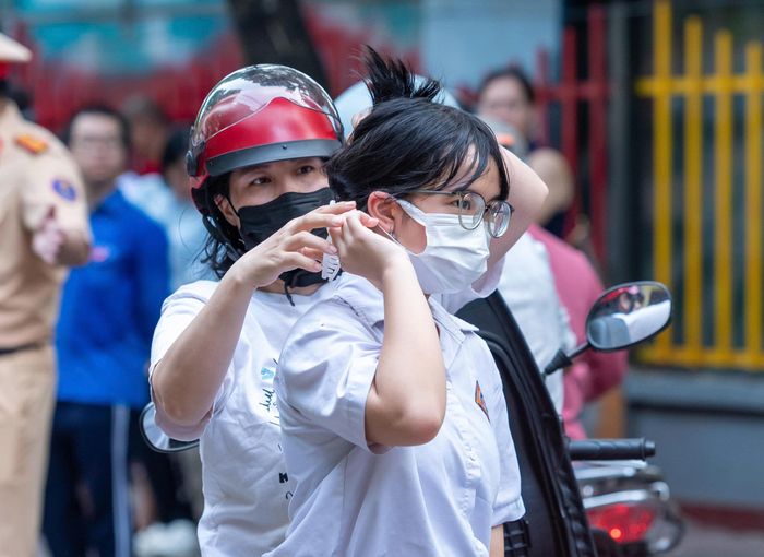Trước giờ thi, phụ huynh tranh thủ chỉnh lại trang phục, buộc gọn mái tóc cho con để các em tự tin bước vào phòng thi. Ảnh: Mạnh Hưng