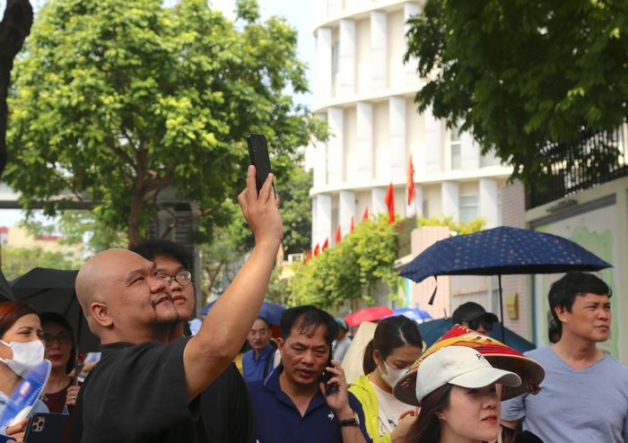 Đứng chờ trước cổng trường, nhiều phụ huynh liên tục hướng ống kính điện thoại về phía lối ra để kịp ghi lại những khoảnh khắc đầu tiên khi các sĩ tử bước ra khỏi cổng trường sau giờ làm bài.