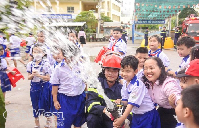 Học sinh Trường Tiểu học Phùng Ngọc Liêm thích thú trải nghiệm thao tác phun nước chữa cháy trong chương trình “Chúng em là lính cứu hỏa”. Ảnh: HỮU THỌ
