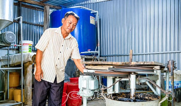 Anh Trần Quốc Khởi bên chiếc máy rang thính tự chế, hỗ trợ vợ trong quá trình làm mắm cá sơn tại cơ sở Ngọc Chuyển. 