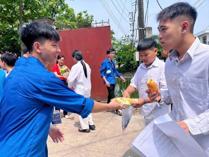 Các thí sinh nhận bánh, sữa tại cổng Trường THPT Trần Đăng Ninh, xã Ứng Thiên. Ảnh: Đoàn Thanh