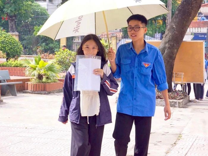 Thanh niên tình nguyện xã Sóc Sơn che nắng cho thí sinh đến đi thi vào lớp 10. Ảnh: Tùng Nguyễn.