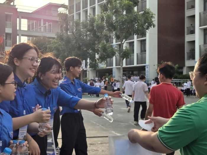 Các tình nguyện viên phát nước uống miễn phí, quạt tay và vật dụng học tập dự phòng cho thí sinh trước giờ làm bài. Ảnh:MK