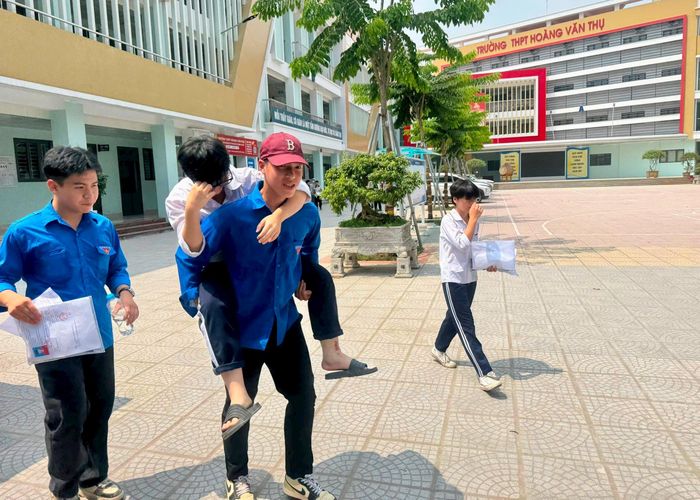 Thanh niên tình nguyện kịp thời vào trường cõng một thí sinh bị đau chân ra khỏi khu vực thi. Ảnh: Trần Oanh