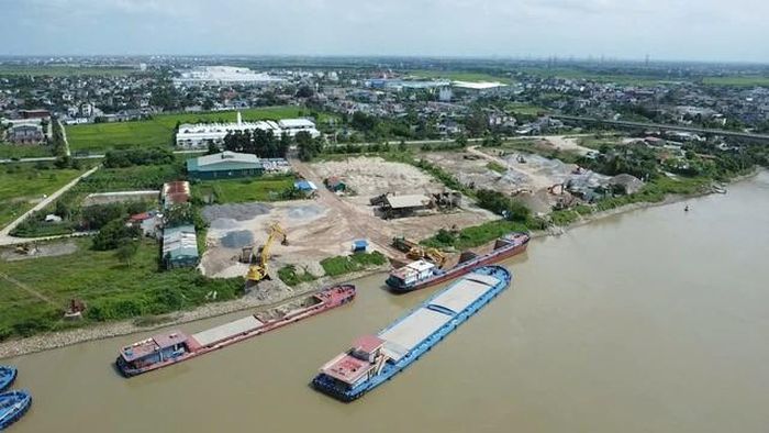 Máy xúc công suất lớn hoạt động liên tục, múc vật liệu trực tiếp từ khoang sà lan lên xe tải.