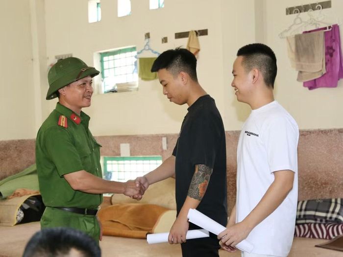 Tại một buồng giam nam, cán bộ Trại tạm giam số 2 bắt tay chúc mừng và căn dặn hai phạm nhân được đặc xá đợt này
