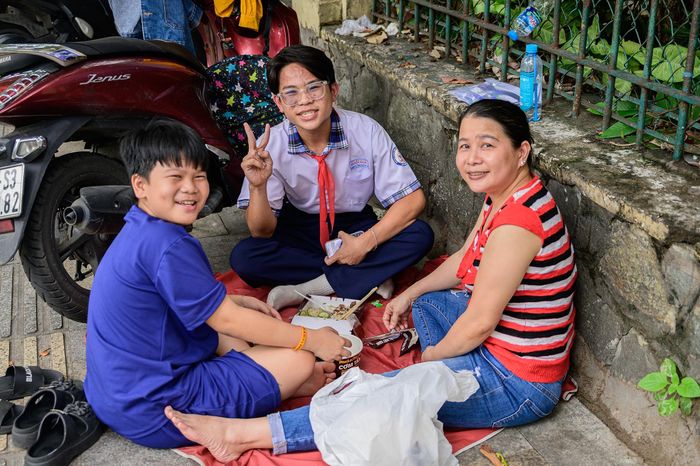  Tại một góc khác trước cổng trường, chị Thanh Thúy (phường Bình Thạnh) tất bật chuẩn bị suất cơm trưa cho con trai là Thanh Duy, học sinh trường THCS Nguyễn Văn Bé. Lo ngại việc di chuyển xa giữa hai buổi thi sẽ khiến con mệt mỏi, chị quyết định ở lại điểm thi để cùng con nghỉ ngơi và dùng bữa. Ngồi cạnh con trong giờ nghỉ trưa ngắn ngủi, chị Thúy cho biết bản thân cũng không tránh khỏi cảm giác hồi hộp. Tuy nhiên, thay vì tạo áp lực về điểm số, chị chỉ mong con giữ được tâm lý thoải mái và làm bài hết khả năng. "Gia đình không đặt nặng thành tích. Điều quan trọng nhất là con tự tin và bình tĩnh trong suốt kỳ thi", chị chia sẻ.