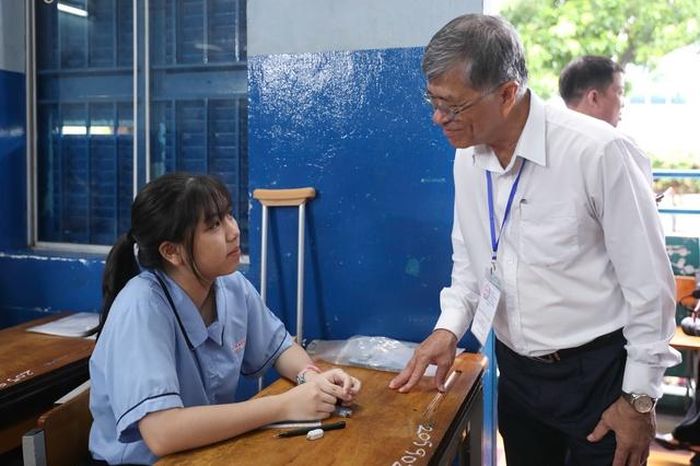 Tại điểm thi Trường THCS Lê Lợi, giám đốc Sở GD-ĐT TPHCM Nguyễn Văn Hiếu động viên tinh thần nữ sinh vì phải chống nạng đi thi