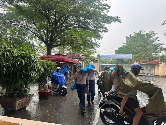 Mưa lớn tại điểm thi Trường THCS Đặng Tấn Tài (phường Phước Long), nhiều phụ huynh chủ động đưa thí sinh đến sớm.