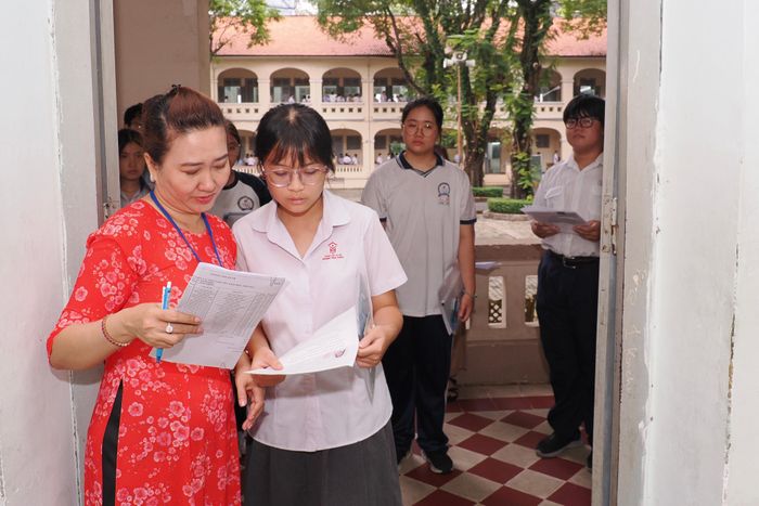  Giám thị hướng dẫn thí sinh đối chiếu thông tin cá nhân trong buổi làm thủ tục dự Kỳ thi tuyển sinh vào lớp 10 THPT năm học 2026-2027 tại điểm thi Trường THPT Chuyên Lê Hồng Phong, phường Chợ Quán. ẢNH: HOÀNG HÙNG. 