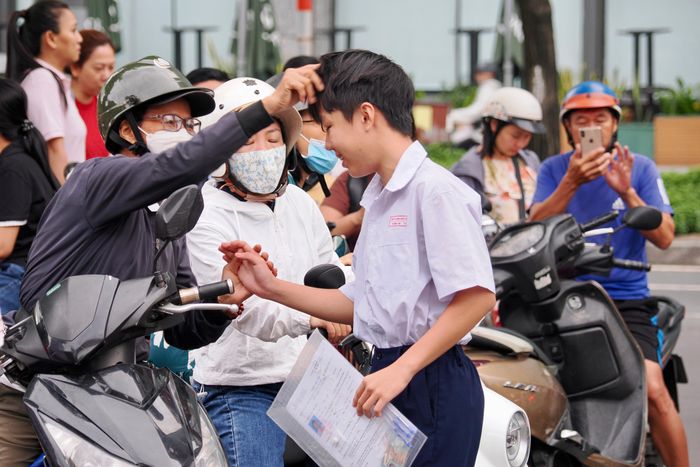  Phụ huynh động viên, chỉnh trang phục cho thí sinh trước giờ dự Kỳ thi tuyển sinh vào lớp 10 THPT năm học 2026-2027 tại điểm thi Trường THPT Chuyên Lê Hồng Phong, phường Chợ Quán. ẢNH: HOÀNG HÙNG. 