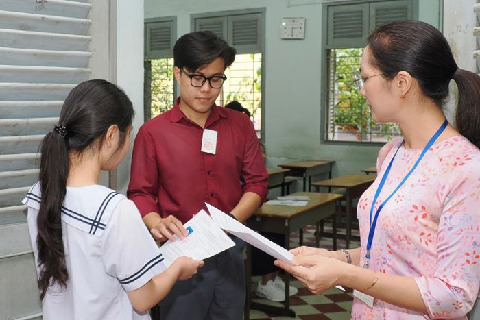  Giám thị kiểm tra giấy tờ, đối chiếu thông tin thí sinh trước giờ thi tại điểm thi Trường THPT Chuyên Lê Hồng Phong, phường Chợ Quán. ẢNH: HOÀNG HÙNG. 