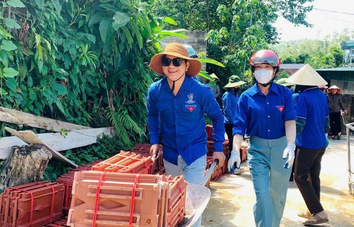 Đoàn viên thanh niên và lực lượng dân quân hỗ trợ vận chuyển vật liệu xây dựng nhà ở cho gia đình chính sách.