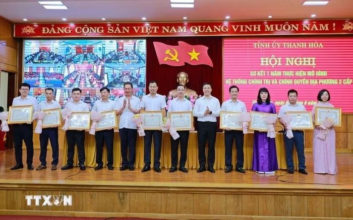Phó Bí thư Thường trực Tỉnh ủy Nguyễn Hồng Phong và Phó Bí thư Tỉnh ủy Trịnh Tuấn Sinh trao Bằng khen của Chủ tịch Ủy ban Nhân dân tỉnh và tặng hoa cho các cá nhân có thành tích xuất sắc trong thực hiện mô hình hệ thống chính trị và chính quyền địa phương 2 cấp. (Ảnh TTXVN phát)