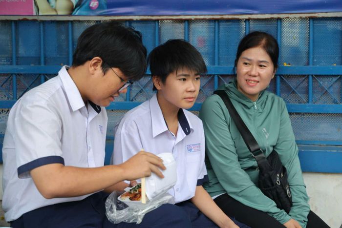 Một phụ huynh động viên và cùng chờ con ăn sáng trước khi đi thi.