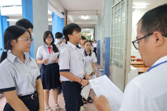 Giám thị kiểm tra thông tin cá nhân và giấy báo dự thi của thí sinh trước khi vào phòng thi tuyển sinh lớp 10 tại điểm thi trường THCS Trường Chinh, phường Bảy Hiền.
