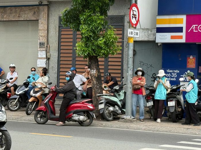 Các phụ huynh đứng bên đường trông sang điểm thi Trường THCS Hai Bà Trưng.