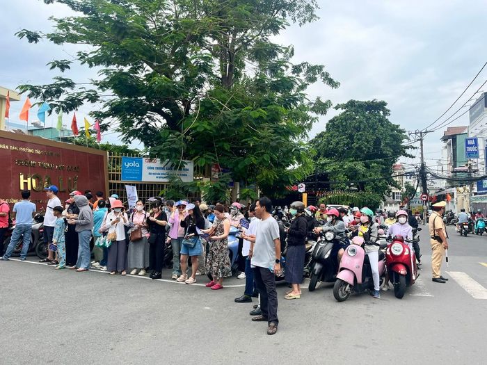 Nhiều phụ huynh kiên nhẫn đứng chờ con ngoài cổng điểm thi Trường THCS Hoa Lư, phường Tăng Nhơn Phú.