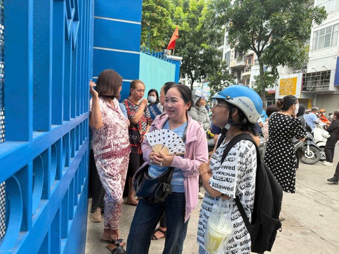 Nhiều phụ huynh trang bị quạt và nước đứng chờ sẵn bên ngoài các điểm thi để đón con mình.