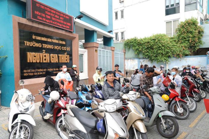 Phụ huynh đứng chờ con trước cổng điểm thi Trường THCS Nguyễn Gia Thiều.