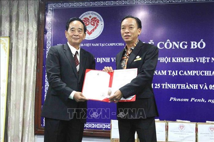 Ông Sim Chy (bên trái), Chủ tịch Tổng hội Khmer - Việt Nam tại Campuchia, trao quyết định và con dấu mới cho ông Nguyễn Văn Cường, Chủ tịch Hội Doanh nhân Campuchia gốc Việt, một trong 5 tổ chức hội trực thuộc Tổng hội. Ảnh: Huỳnh Thảo/PV TTXVN tại Campuchia