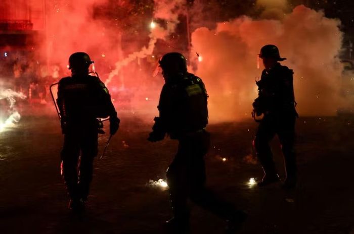 Các sĩ quan cảnh sát tự bảo vệ mình khỏi pháo sáng sau khi Paris Saint-Germain giành chiến thắng UEFA Champions League. Ảnh: Reuters.