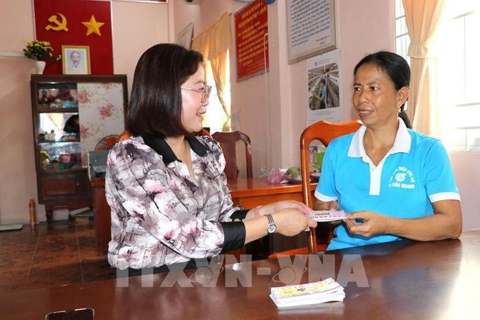 Bà Võ Thị Hồng Dung, Chủ tịch Hội Liên hiệp Phụ nữ xã Cầu Ngang (bên trái) giao vé số cho Chi hội phụ nữ ấp Mỹ Cẩm B bán để gây quỹ hỗ trợ phụ nữ có hoàn cảnh khó khăn theo mô hình "Vé số yêu thương". Ảnh: Thanh Hòa - TTXVN