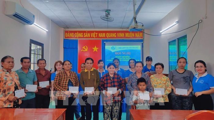 Hội Liên hiệp Phụ nữ xã Cầu Ngang trao tiền hỗ trợ phụ nữ có hoàn cảnh khó khăn từ nguồn bán vé số gây quỹ. Ảnh: TTXVN phát