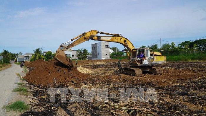 Máy móc đắp bờ bao để bơm cát san lấp mặt bằng, thi công Dự án trường Phổ thông nội trú Tiểu học - THCS Thường Phước. Ảnh: Nhựt An - TTXVN