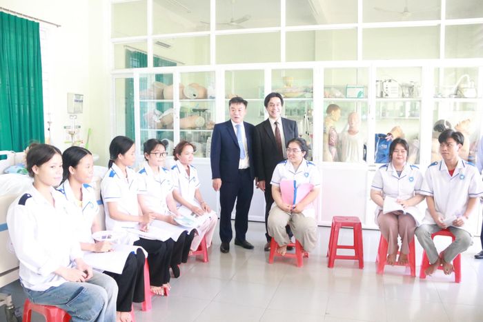 Ông Bùi Long Ẩn - quyền Hiệu trưởng nhà trường (thứ 6, bên trái sang) và ông Kataoka Yoshikazu - Giám đốc điều hành Tổ chức Phúc lợi quốc tế Nhật Bản (thứ 4, bên phải sang) thăm sinh viên điều dưỡng nhà trường. Ảnh: HOÀNG LIÊN