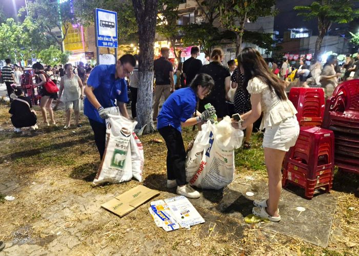 Du khách cùng các tình nguyện viên tham gia dọn rác sau đêm trình diễn pháo hoa quốc tế. Ảnh: NGỌC QUỐC