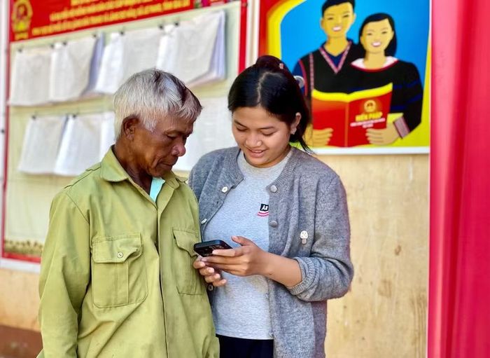 Chị Yuệ (làng Dơ Nâu, xã Lơ Pang) hướng dẫn người dân truy cập internet trên điện thoại thông minh để tìm hiểu thông tin. Ảnh: V.T