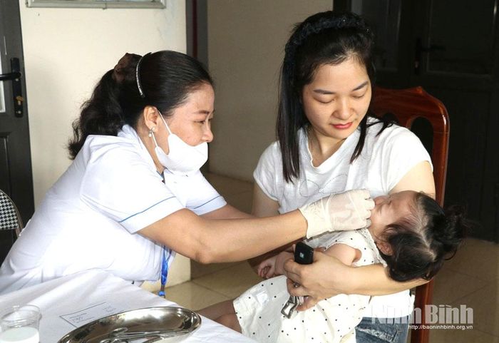 Cán bộ Trạm Y tế phường Hoa Lư cho trẻ bổ sung Vitamin A.